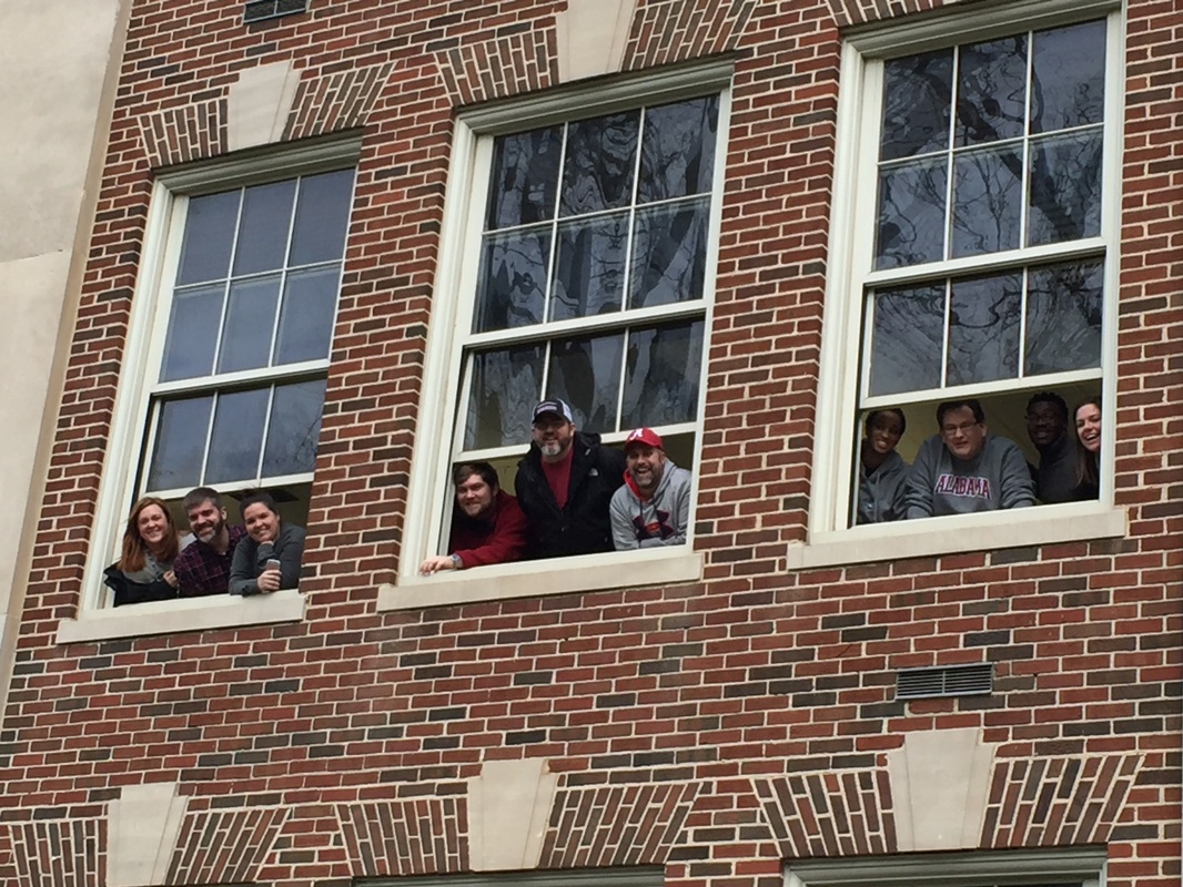 Outside view of 10 students looking out window to watch parade